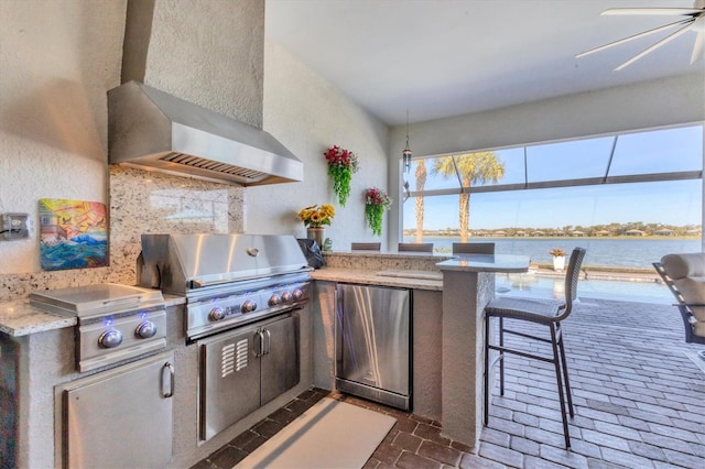 view of patio featuring a water view, an outdoor kitchen, a grill, and a bar