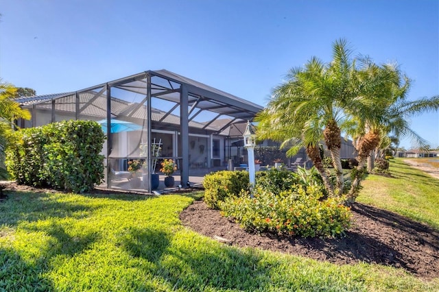 back of property featuring a lanai and a lawn