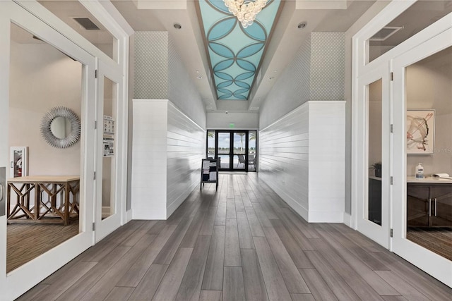 corridor featuring a notable chandelier, hardwood / wood-style flooring, and a high ceiling