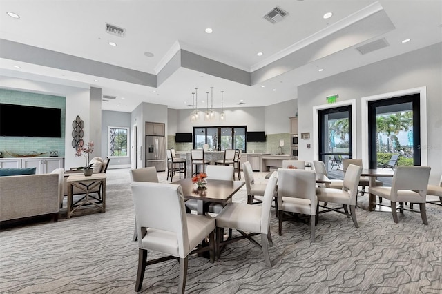 carpeted dining room featuring a raised ceiling, ornamental molding, and a towering ceiling