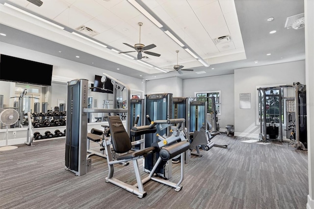 exercise room featuring carpet flooring, ceiling fan, and a tray ceiling