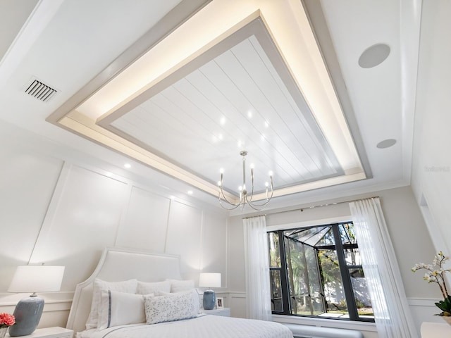 bedroom featuring ornamental molding, a tray ceiling, and a notable chandelier