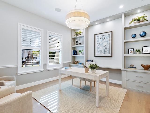 office space with built in shelves and light hardwood / wood-style floors