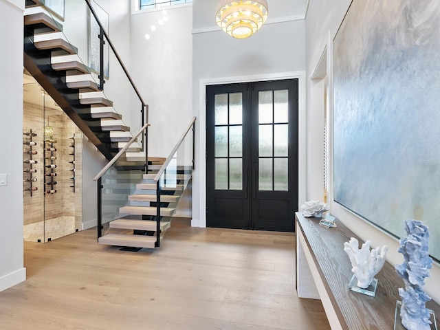 foyer featuring light hardwood / wood-style flooring, french doors, a healthy amount of sunlight, and a high ceiling