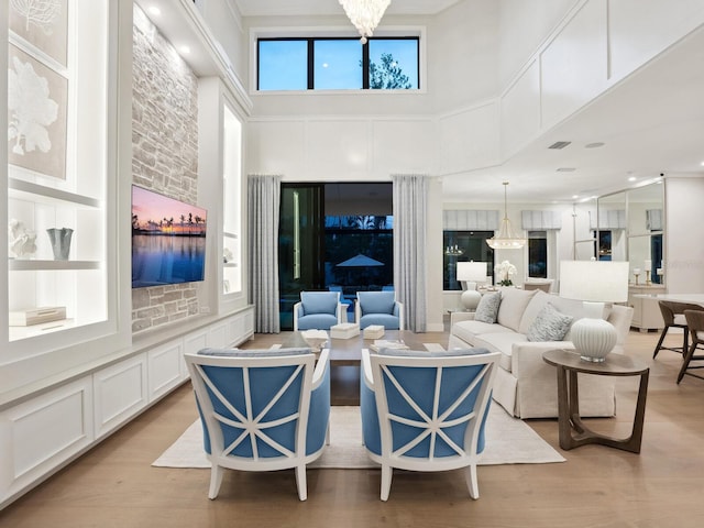 living room with a high ceiling, a chandelier, and light hardwood / wood-style flooring