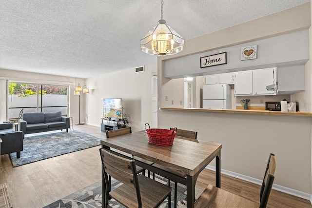 dining area featuring light hardwood / wood-style floors and a textured ceiling