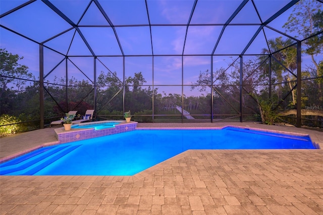 pool at dusk with an in ground hot tub, a patio, and glass enclosure