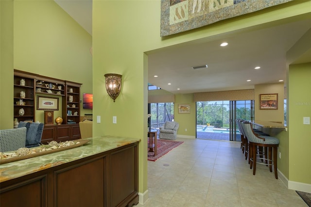 interior space featuring baseboards, a high ceiling, visible vents, and recessed lighting