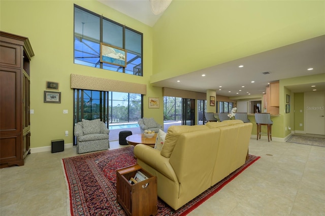 living room featuring light tile patterned floors, recessed lighting, a high ceiling, visible vents, and baseboards