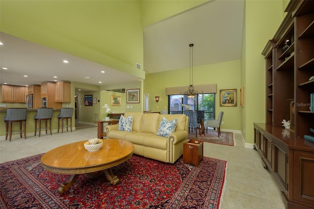 living area with light tile patterned floors, recessed lighting, visible vents, a high ceiling, and baseboards