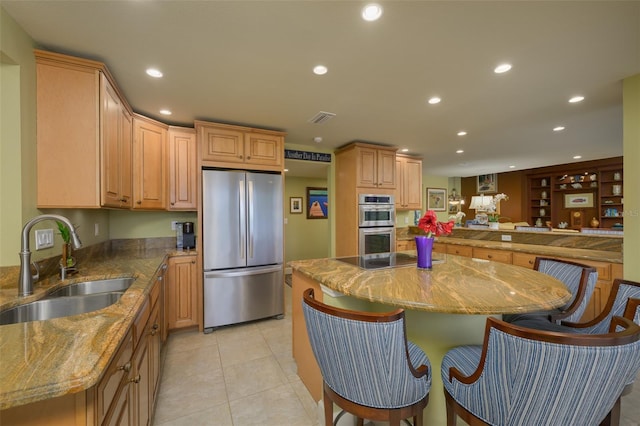 kitchen featuring recessed lighting, a breakfast bar, a sink, appliances with stainless steel finishes, and a center island