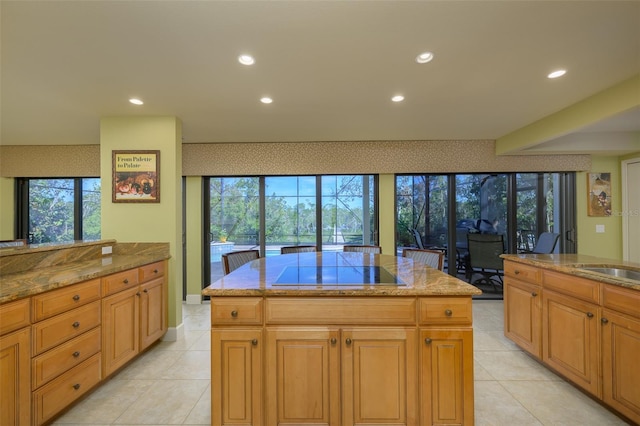 kitchen with stone counters, a center island, black electric cooktop, and recessed lighting