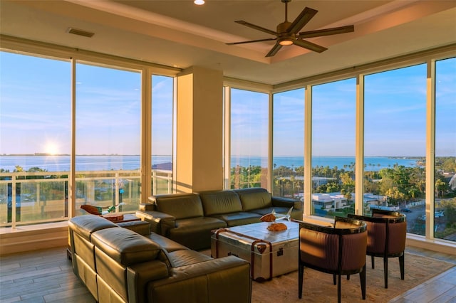 sunroom / solarium featuring a water view, plenty of natural light, and ceiling fan