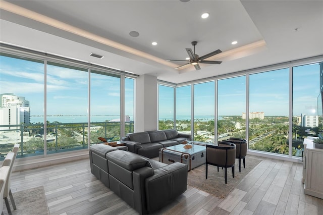 sunroom with a water view, ceiling fan, a healthy amount of sunlight, and a raised ceiling