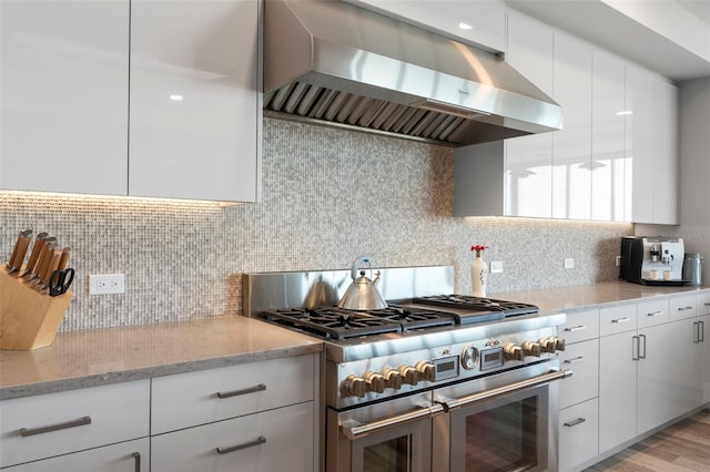 kitchen featuring double oven range, decorative backsplash, range hood, and white cabinets