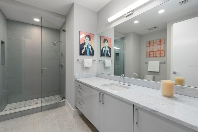 bathroom featuring vanity, a shower with shower door, and toilet