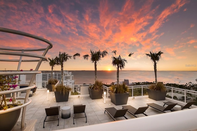 patio terrace at dusk featuring a water view