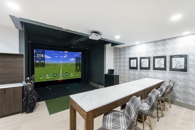 cinema room with golf simulator and light wood-type flooring