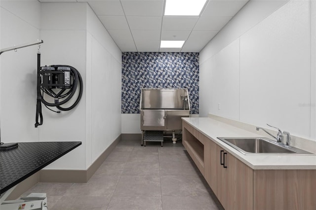 kitchen featuring sink, a paneled ceiling, white cabinets, and light tile patterned floors