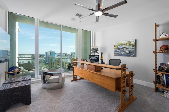 carpeted home office featuring ceiling fan and a wall of windows