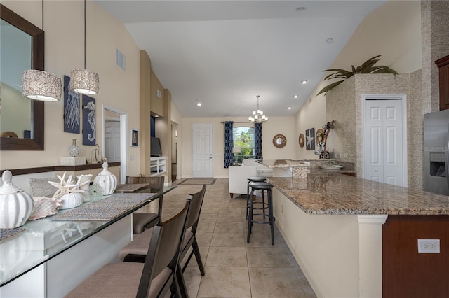 kitchen featuring light tile patterned flooring, pendant lighting, stainless steel fridge, a chandelier, and a kitchen bar