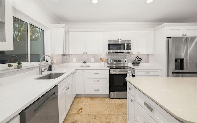 kitchen featuring sink, white cabinetry, ornamental molding, appliances with stainless steel finishes, and decorative backsplash