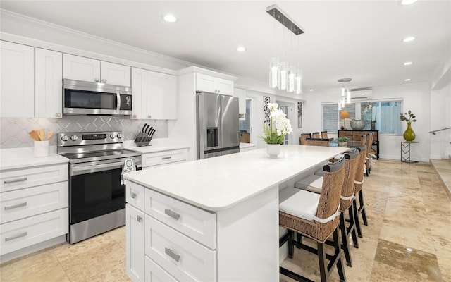 kitchen featuring white cabinetry, a center island, a wall unit AC, pendant lighting, and stainless steel appliances