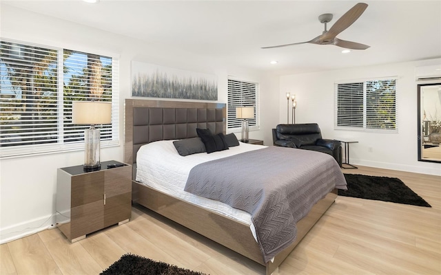 bedroom with ceiling fan, light hardwood / wood-style floors, and a wall unit AC