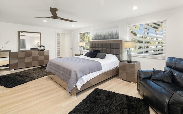 bedroom featuring ceiling fan, multiple windows, and light hardwood / wood-style flooring