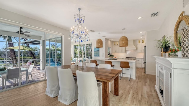 dining room with ceiling fan with notable chandelier and light hardwood / wood-style flooring