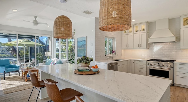 kitchen featuring pendant lighting, custom exhaust hood, white cabinets, and appliances with stainless steel finishes