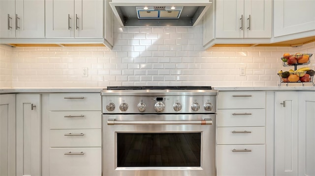 kitchen featuring white cabinetry, high end stainless steel range, tasteful backsplash, and wall chimney range hood