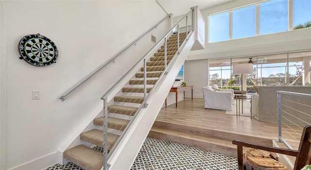 staircase with a towering ceiling and hardwood / wood-style floors