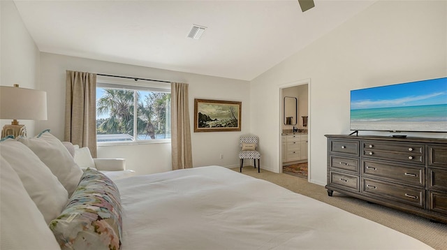 bedroom with connected bathroom, vaulted ceiling, and light colored carpet