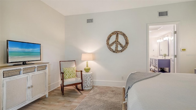 bedroom featuring connected bathroom and light hardwood / wood-style floors