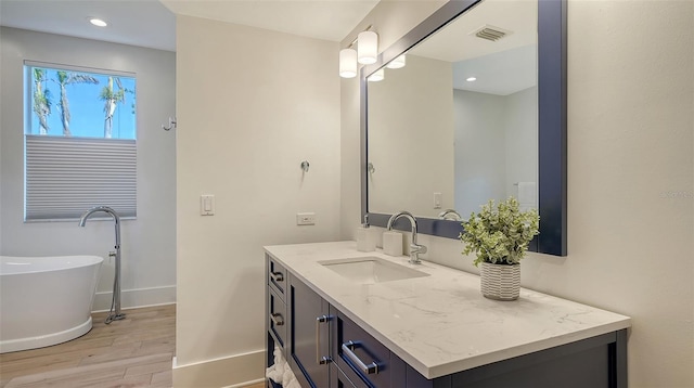 bathroom featuring hardwood / wood-style flooring, vanity, and a washtub