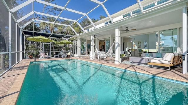 view of pool with a patio area, outdoor lounge area, ceiling fan, and glass enclosure