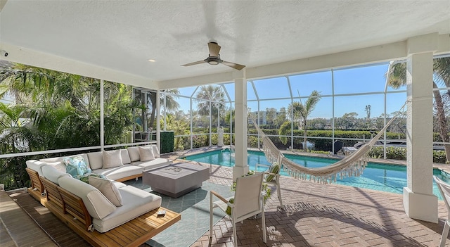 sunroom featuring a patio, an outdoor living space with a fire pit, and ceiling fan