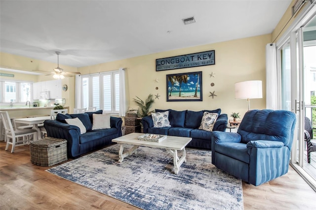 living room featuring sink, light hardwood / wood-style floors, and ceiling fan