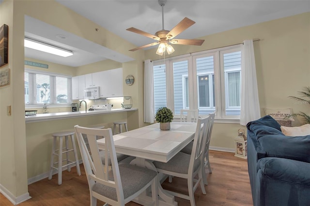 dining room featuring wood-type flooring, sink, and ceiling fan