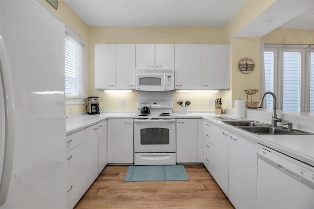 kitchen with white cabinetry, sink, white appliances, and light hardwood / wood-style floors