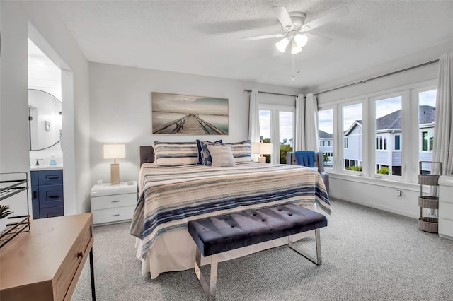 carpeted bedroom featuring ceiling fan, sink, and a textured ceiling