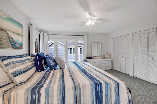 carpeted bedroom with ceiling fan, two closets, access to outside, and a textured ceiling