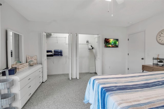 bedroom with ceiling fan, light colored carpet, and multiple closets