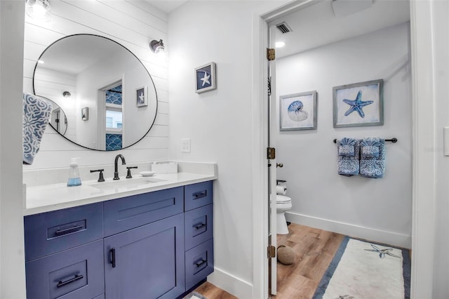 bathroom with vanity, toilet, and hardwood / wood-style floors