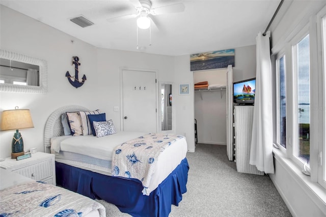 carpeted bedroom with a walk in closet, a closet, and ceiling fan