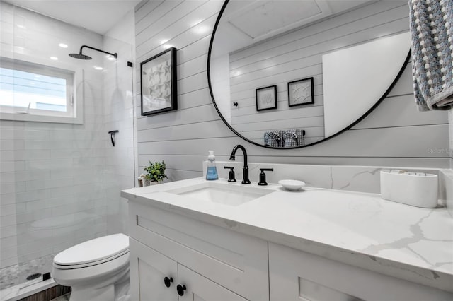 bathroom with wooden walls, vanity, toilet, and a tile shower