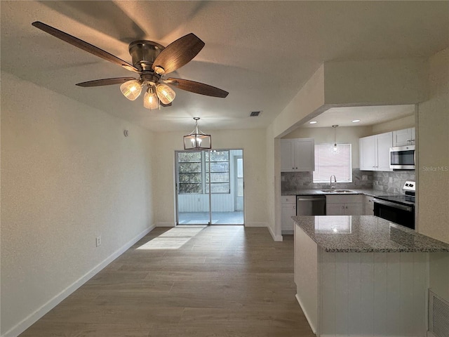 kitchen with sink, dark stone counters, stainless steel appliances, decorative backsplash, and white cabinets