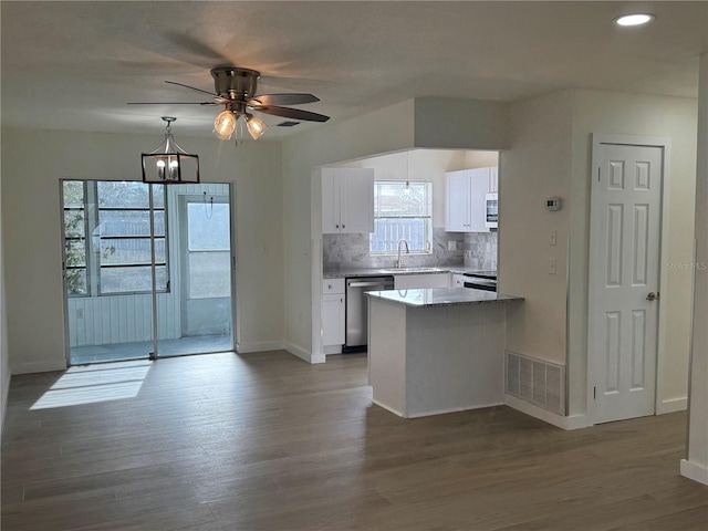 kitchen featuring stainless steel dishwasher, white cabinets, hardwood / wood-style flooring, ceiling fan, and backsplash