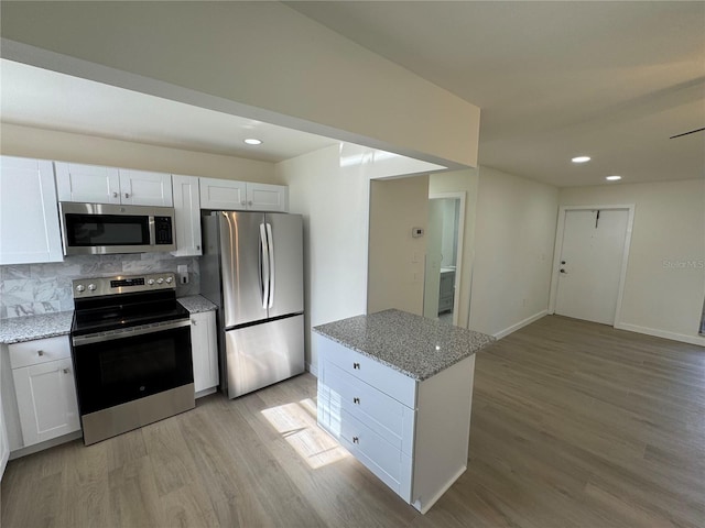 kitchen featuring stainless steel appliances, white cabinetry, light stone counters, and light hardwood / wood-style flooring